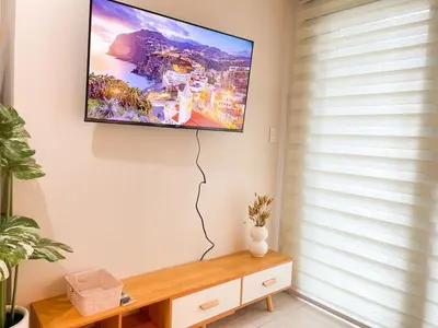 a flat screen tv hanging on a wall at Elegant BGC Condo Across Mitsukoshi Mall #upt27p in Manila