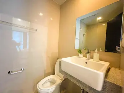 a bathroom with a sink and a toilet and a mirror at Elegant BGC Condo Across Mitsukoshi Mall #upt27p in Manila
