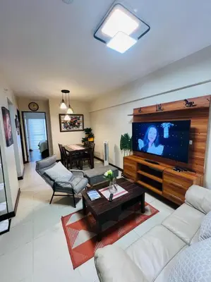 a living room with a flat screen tv and a couch at 2-bedroom with Balcony in a Resort Setting - H Ivory in Manila