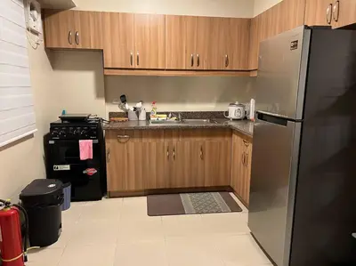 a kitchen with wooden cabinets and a stainless steel refrigerator at 2-bedroom with Balcony in a Resort Setting - H Ivory in Manila