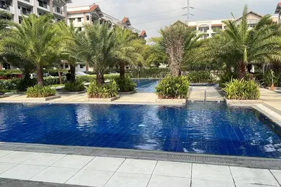 a large blue swimming pool with palm trees and buildings at 2-bedroom with Balcony in a Resort Setting - H Ivory in Manila