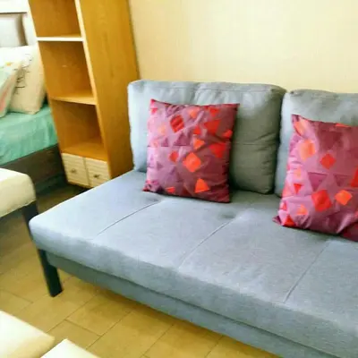 a blue couch with two red pillows on it at Eastwood Legrand Tower 3 condominium in Manila