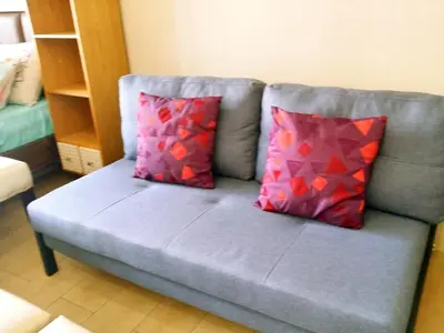 a blue couch with two red pillows on it at Eastwood Legrand Tower 3 condominium in Manila