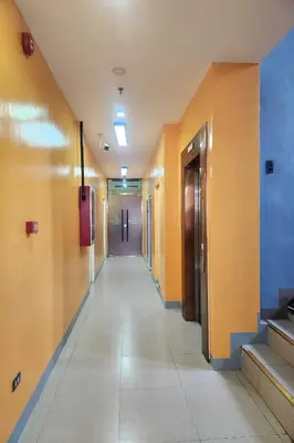 an empty hallway in a hospital with yellow walls at Qingqing Hotel Pasay Manila near MOA in Manila
