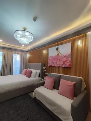 a hotel room with two beds and a couch at Georgia Luxe Suite at Shore 2 MOA in Manila