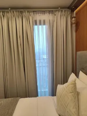 a bedroom with a bed and a window with curtains at Georgia Luxe Suite at Shore 2 MOA in Manila