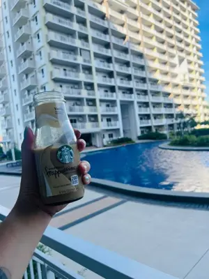 a person holding a beer in front of a building at Gina Staycation Condo Unit in Manila