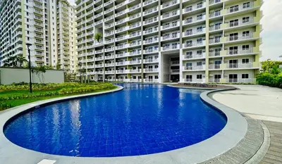a swimming pool in front of a large apartment building at Gina Staycation The Atherton DMCI Parañaque in Manila