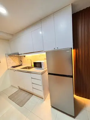 a kitchen with white cabinets and a stainless steel refrigerator at LA Amore Place Aspire Tower Nuvo City Libis in Manila