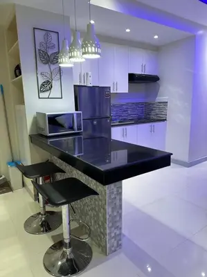 a kitchen with a black counter and two bar stools at The Quin Place 1BR 200Mbps WIFI in Manila