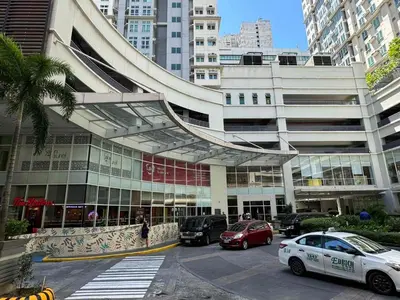 a large building with cars parked in a parking lot at The Quin Place 1BR 200Mbps WIFI in Manila