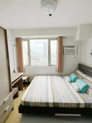 a bedroom with a large bed with a window at Fully Furnished 1BR Ridgewood Towers with 200Mbps WIFI in Manila