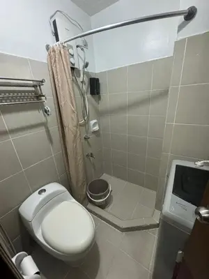 a small bathroom with a toilet and a shower at Fully Furnished 1BR Ridgewood Towers with 200Mbps WIFI in Manila