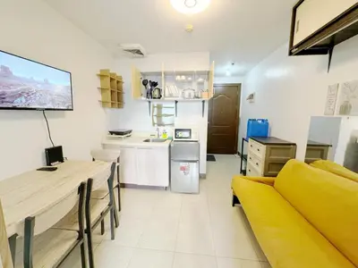 a living room with a yellow couch and a kitchen at Fully Furnished 1BR Ridgewood Towers with 200Mbps WIFI in Manila