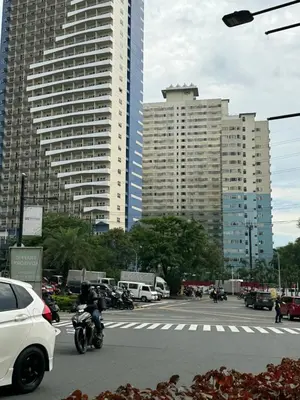 a person riding a motorcycle on a street with tall buildings at Fully Furnished 1BR Ridgewood Towers with 200Mbps WIFI in Manila