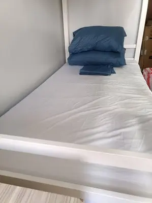 a white bed with a blue pillow on it at Lorde's Hideaway in Manila