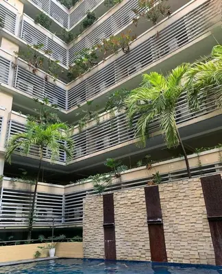 a building with palm trees in front of it at 1 Bed Apartment - Sleeps 7 - Pool & Wifi in Manila