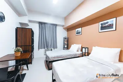 a hotel room with two beds and a desk at The City Flats Circuit in Manila