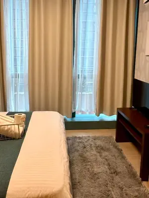a bedroom with a bed and a dresser and windows at BGC One Uptown Suite by Christine Suites PH in Manila