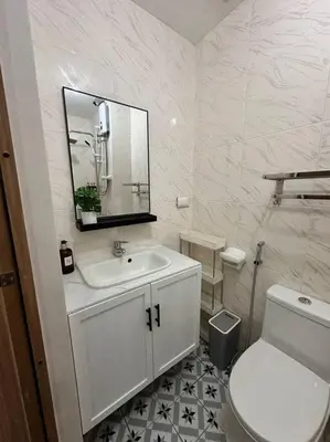 a white bathroom with a sink and a toilet at Cozy Condo in Taguig in Manila