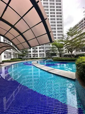 a large swimming pool with blue water in a city at Cozy Condo in Taguig in Manila