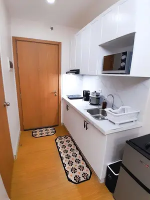 a small kitchen with a sink and a door at Cozy Condo in Taguig in Manila