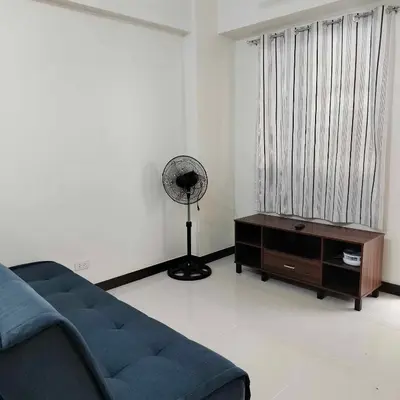 a living room with a blue couch and a fan at Satori Residence in Manila