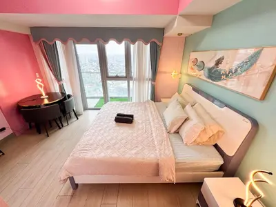 a bedroom with a bed and a desk and a window at Elegant 4BR with balcony and bathtub in Uptown BGC in Manila