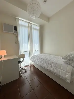 a bedroom with a bed and a desk and a window at Hayahay Vacay in Manila