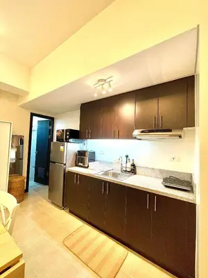a kitchen with dark brown cabinets and a sink at Hayahay Vacay in Manila