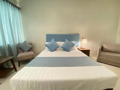a bedroom with a large bed with two blue pillows at UPad Hotel in Manila