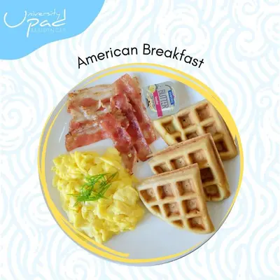a plate of american breakfast with waffles and bacon at UPad Hotel in Manila