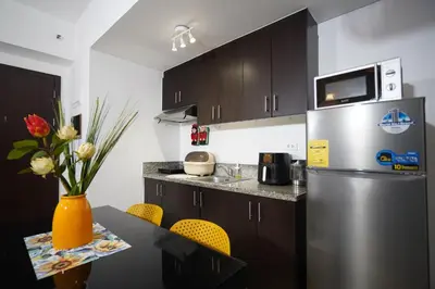 a kitchen with a refrigerator and a table with chairs at Hayahay Rentals in Manila