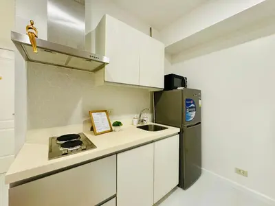 a kitchen with white cabinets and a stainless steel refrigerator at Masies Beach View Suite at Azure Urban Resort Residences in Manila
