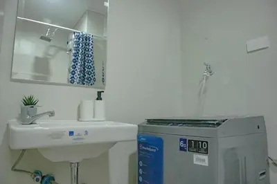 a white bathroom with a sink and a mirror at Quiet Oasis in Bloom Residences in Manila