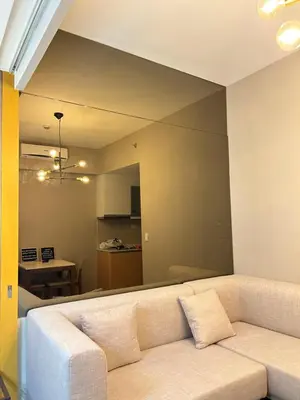 a living room with a white couch and a kitchen at One Uptown Residences BGC in Manila
