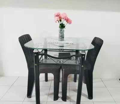 a glass table with two chairs and a vase with flowers at Belthena Suite in Las Piñas Near Airport in Manila