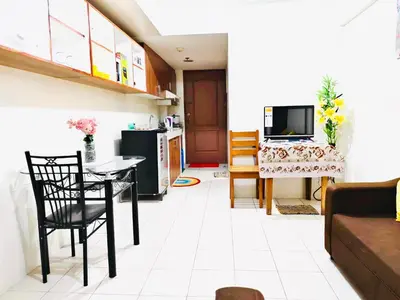 a kitchen and living room with a table and a tv at Belthena Suite in Las Piñas Near Airport in Manila