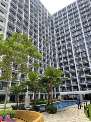 a large apartment building with a swimming pool and palm trees at Premium Condotel Close To MOA in Manila