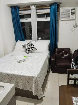 a bedroom with a bed and a chair and a window at Nicecondote in Manila