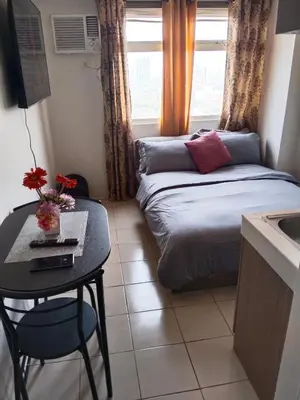 a small room with a bed and a table and a window at Nicecondote in Manila