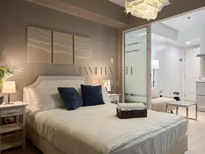 a bedroom with a large white bed with blue pillows at Miami Haven at Azure in Manila