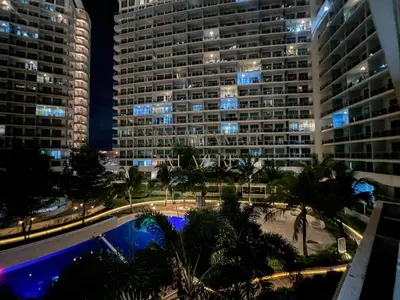 a view of a large building with palm trees and a pool at Miami Haven at Azure in Manila