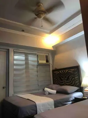 a bedroom with two beds and a window with a fan at COMFY 1-BR Condo near SLEC, US Embassy, Malls,Park in Manila