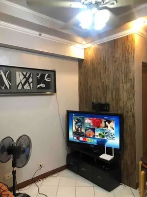 a flat screen tv sitting on a stand in a room at COMFY 1-BR Condo near SLEC, US Embassy, Malls,Park in Manila