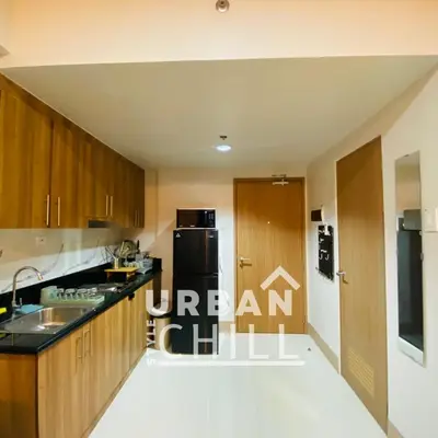 a kitchen with wooden cabinets and a black counter top at Urban Style Chill, Shore 3, MOA Complex, Pasay, Manila in Manila