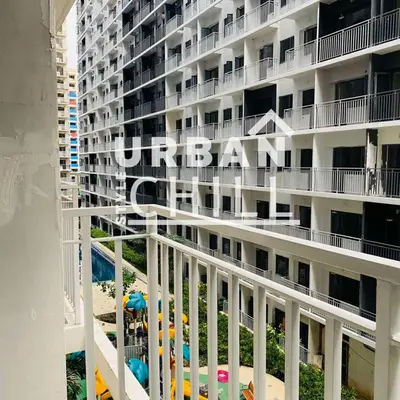 a large white building with a swimming pool next to a beach at Urban Style Chill, Shore 3, MOA Complex, Pasay, Manila in Manila
