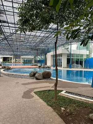 a building with a swimming pool with a tree in it at 1BR Cozy Condo at Kasara Urban Resort Pasig City in Manila