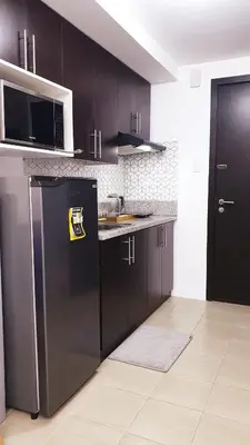 a kitchen with black cabinets and a black refrigerator at 1BR Cozy Condo at Kasara Urban Resort Pasig City in Manila