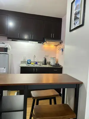 a kitchen with black cabinets and a wooden table at Solstay in Manila